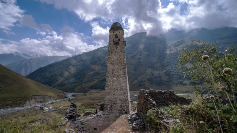 a tall stone tower in a mountainous landscape