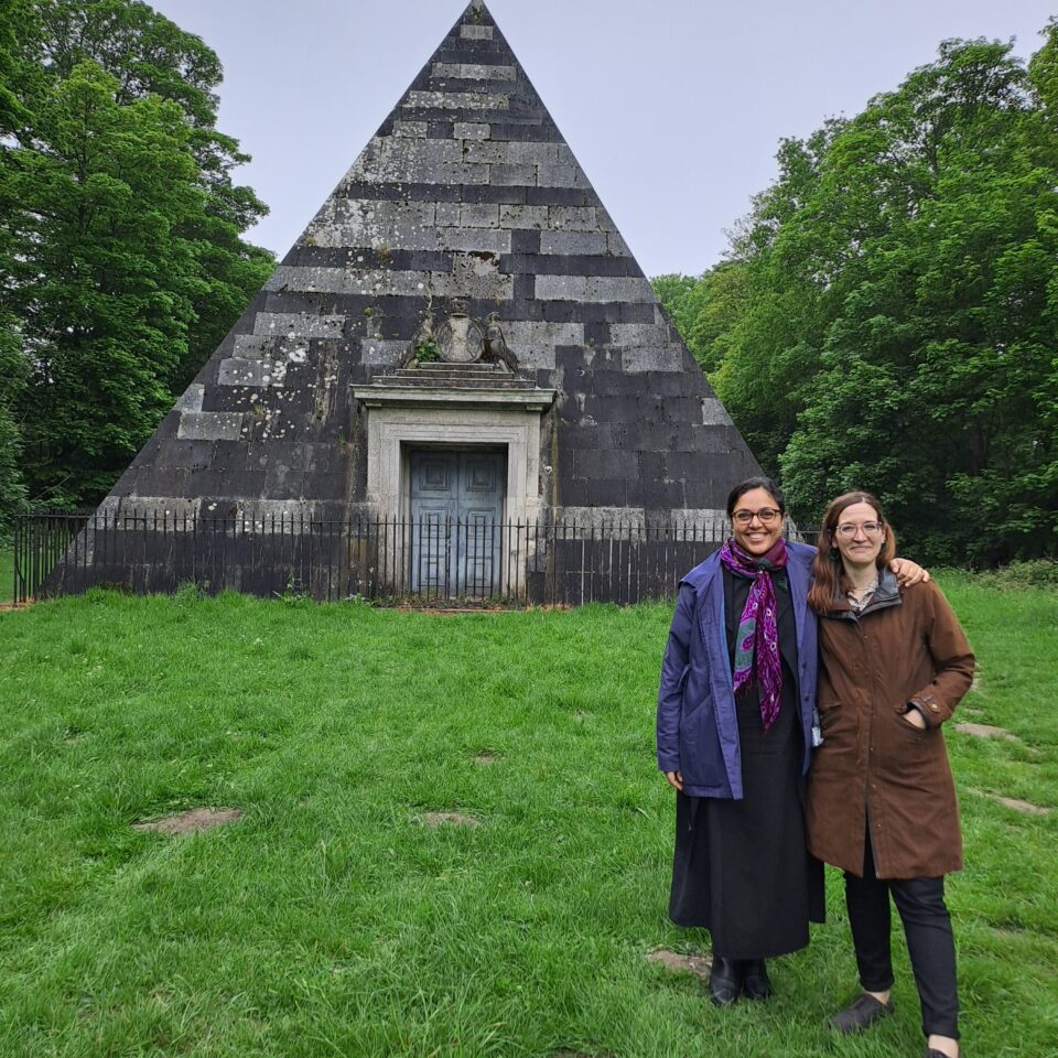 two women looking at the garden at Blickling estate posing in front a pyramid structure
