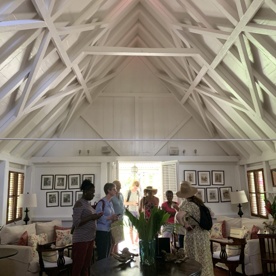 A small group of people on a guided tour of a wooden building with a white painted interior