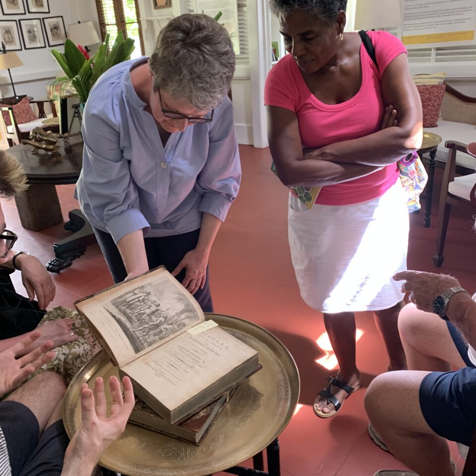 two women examining an historic book, with two other people slightly off camera - only their hands or knees are visible - for the blog whose past