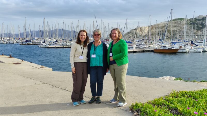 Three people from INTO, NTS and NT, standing in a port in Frioul, France