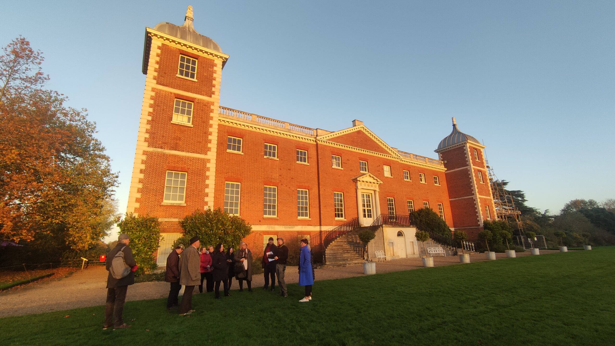 People outside an old building on a sunny evening