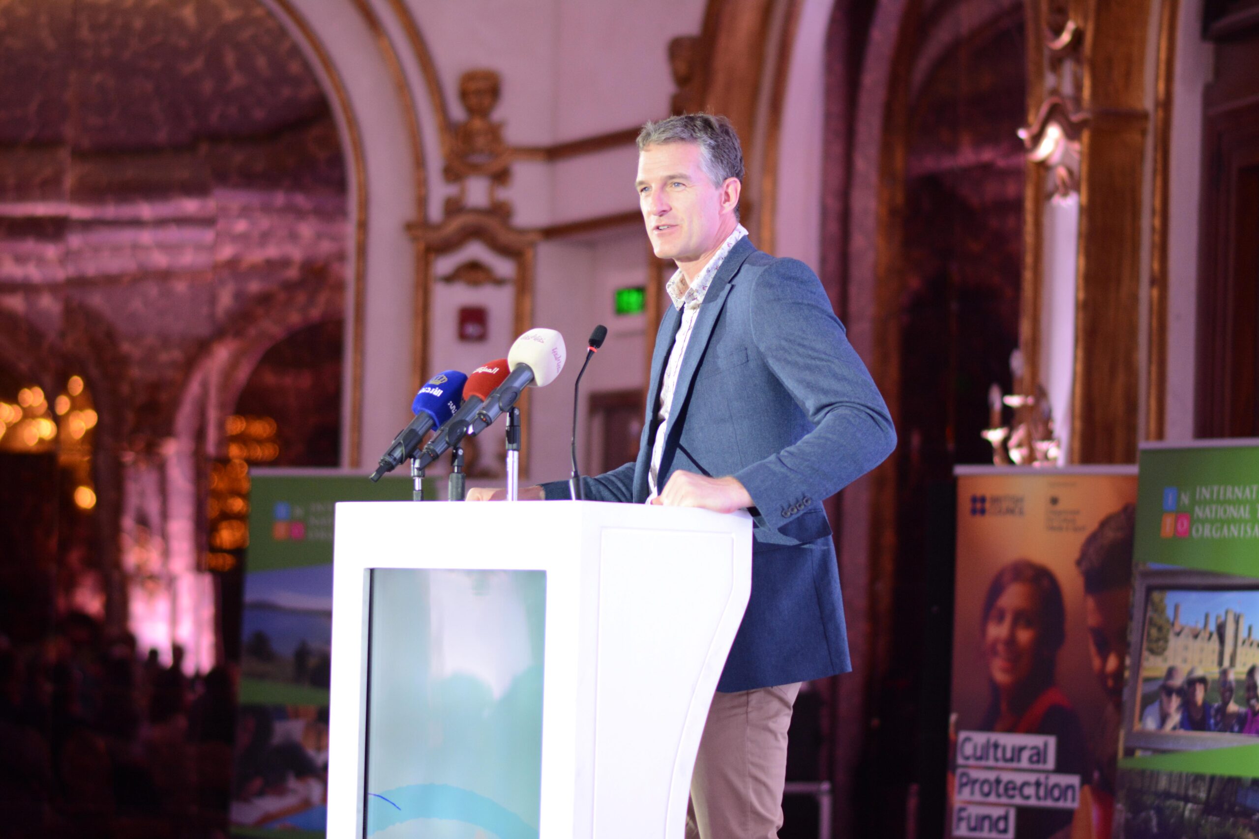 a man giving a presentation at a lectern in a grand room